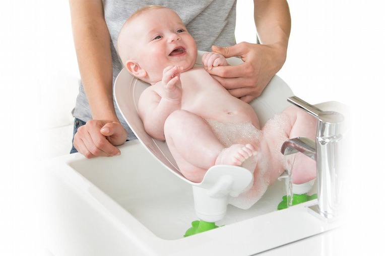 A baby sitting on a Chicco Coccola chair, washing it's bottom