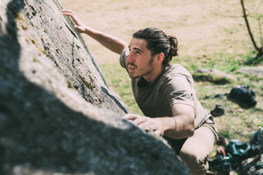 young-male-boulderer-climbing-up-boulder-lombardy